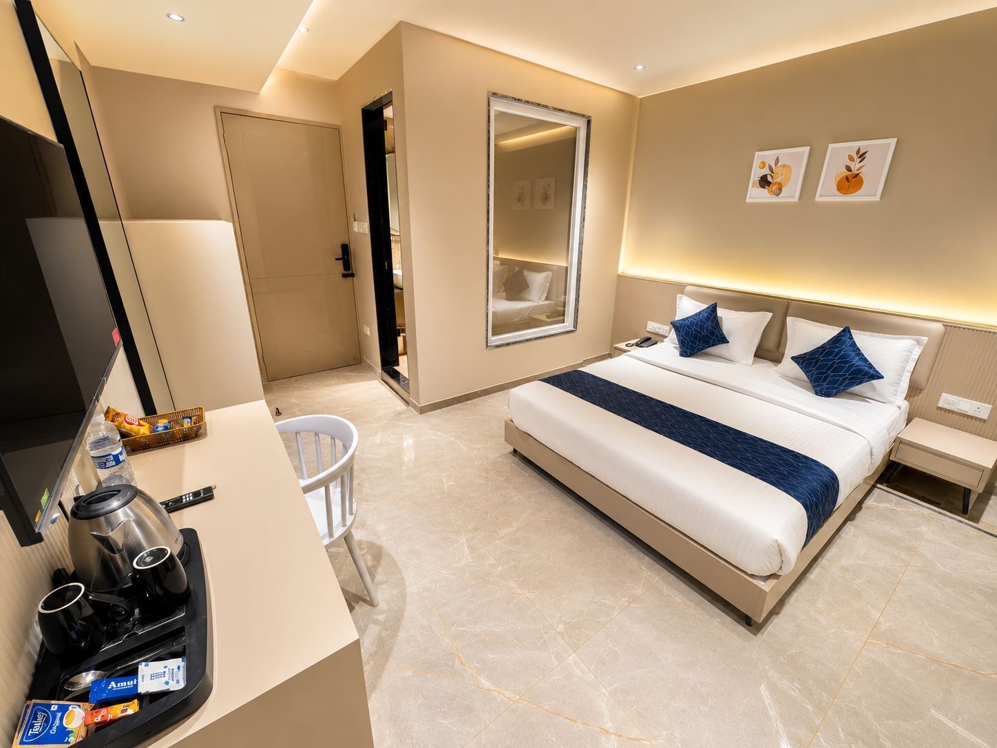 Habitación de hotel con cama, mesitas de noche, espejo, espacio para café y armario.