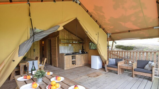 Alojamento em tenda com cozinha, sala de jantar e área de estar.