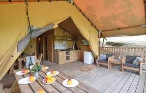 Eine Zelthütte mit Küche, Essbereich und Sitzgelegenheiten.