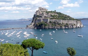A coastal town with a prominent castle on a hill, surrounded by water and boats. - Amazing home in Casamicciola Terme with sauna (Casamicciola Terme)