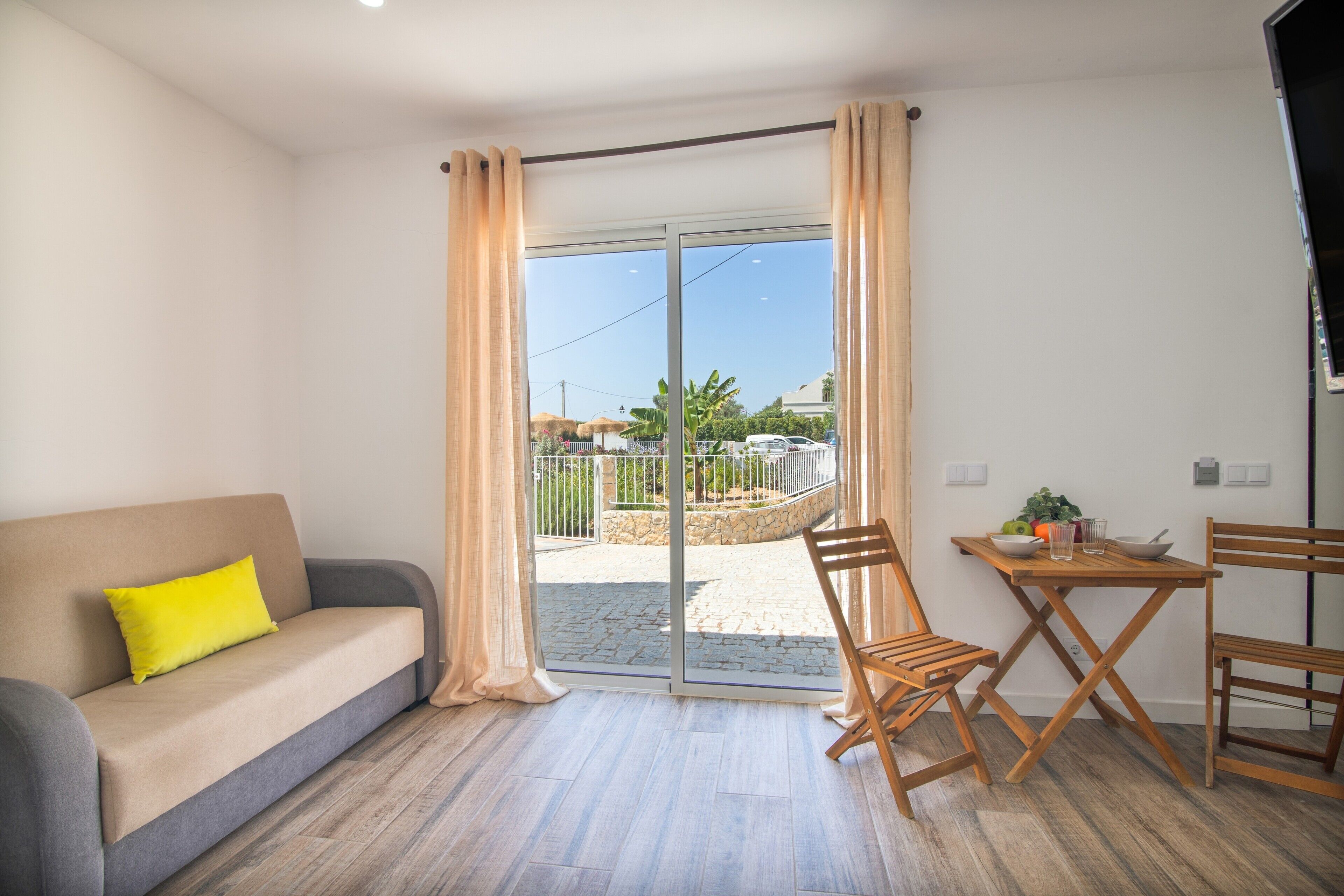 Ein Zimmer mit einer Sitzecke, einem Esstisch, Stühlen und einer Glastür, die zu einem Außenbereich führt.