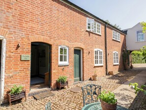 A brick building with a sign reading 'The Stable Flat,' a cobblestone courtyard, and outdoor seating. - The Stable Flat (Lutterworth)