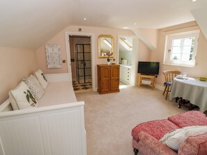 A bedroom with a bed, a TV, a desk, and a chair. - The Stable Flat (Lutterworth)