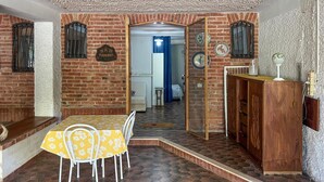 Ein Essbereich mit Backsteinwand, einem Tisch mit Stühlen, einem Holzschrank und einem Spiegel.