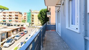 A balcony with a view of a city street, buildings, and parked cars. - Appartamento Monteverde Casa Marí Roma (Roma)