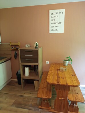 Una cucina con mobili in legno, un tavolo di legno e un cartello appeso al muro.