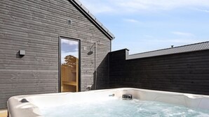 Un espace détente avec un jacuzzi, des murs en bois et une porte donnant accès à un bâtiment.