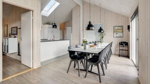 Une cuisine moderne avec des meubles blancs, un coin repas comprenant une table et des chaises, et un plancher en bois.