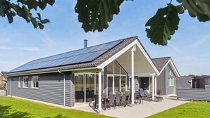 Une maison moderne dotée d’un patio couvert, de panneaux solaires et d’une pelouse bien entretenue.
