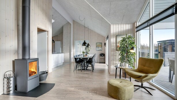 Un salon moderne avec un poêle à bois, un coin repas et une grande fenêtre.