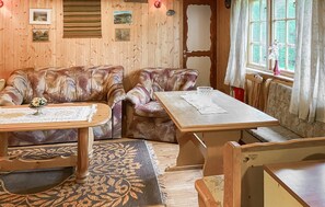 Ein gemütliches Zimmer mit Holzeinrichtung, einer Couch, einem Tisch und einem Fenster mit Vorhängen.