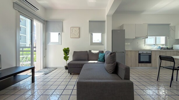 Una sala de estar moderna con un sofá modular gris, una mesita y una planta en maceta.