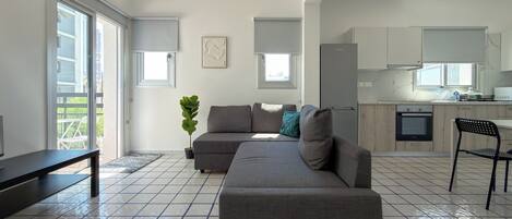 Uma sala de estar moderna com um sofá modular cinza, uma mesa pequena e uma planta em vaso.