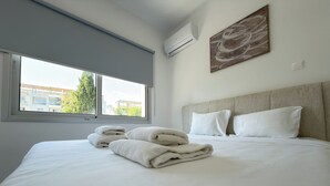 Habitación de hotel con una cama grande, ventana con vistas, aire acondicionado y un cuadro en la pared.