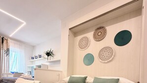 A modern hotel room with a neatly made bed, a desk, and decorative wall art.