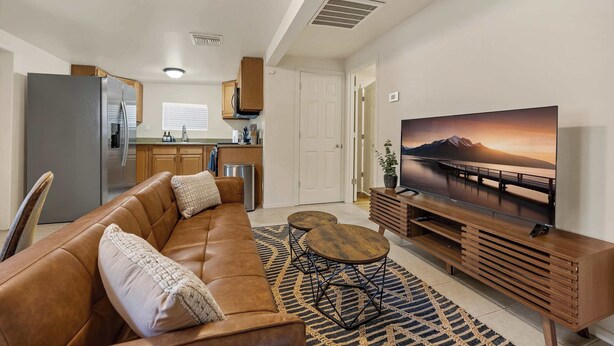 A modern living room with a sofa, coffee table, TV, and kitchen area.