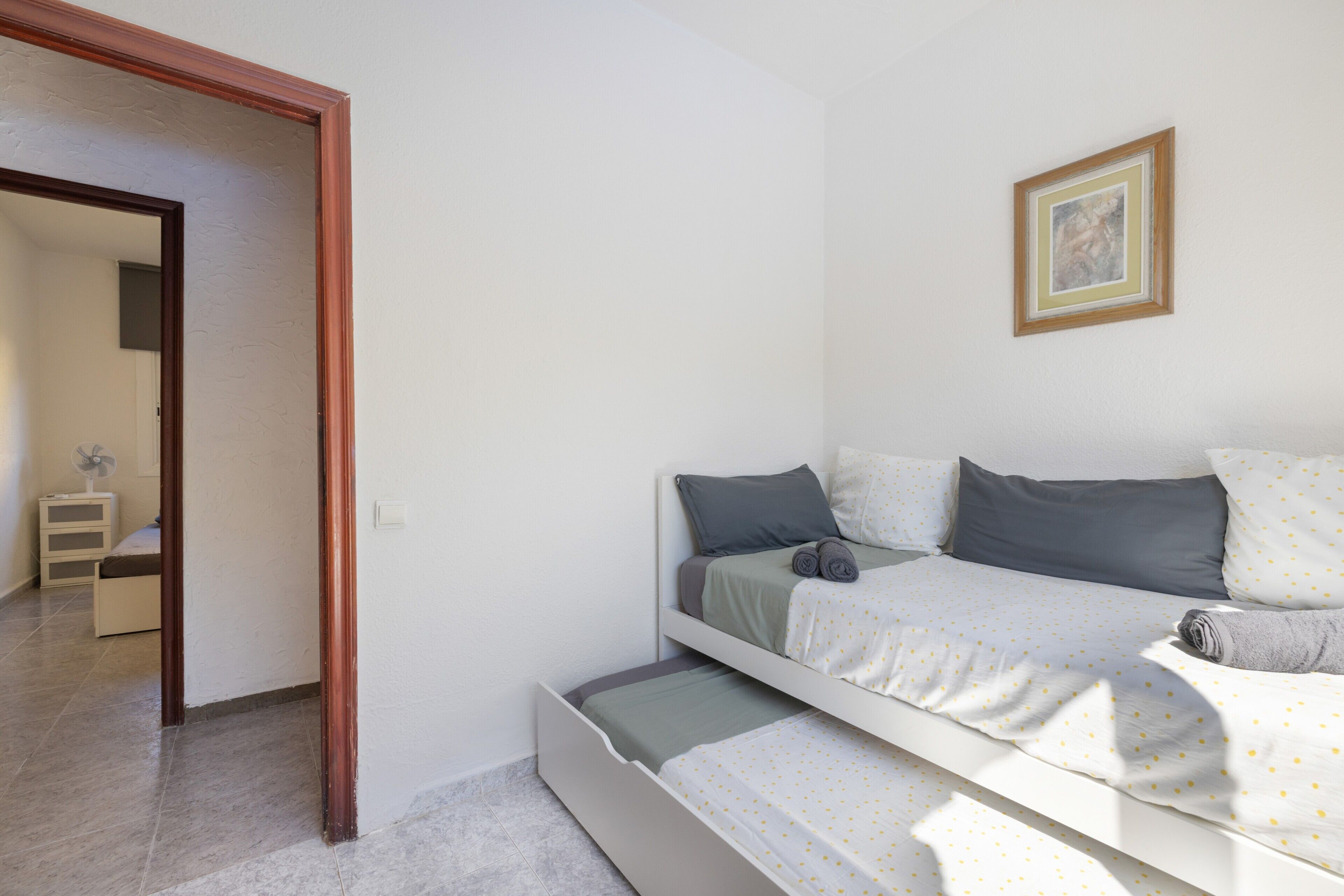 Ein Schlafzimmer mit einem Bett, einem Nachttisch, einem Sessel und einer Tür zu einem anderen Raum.