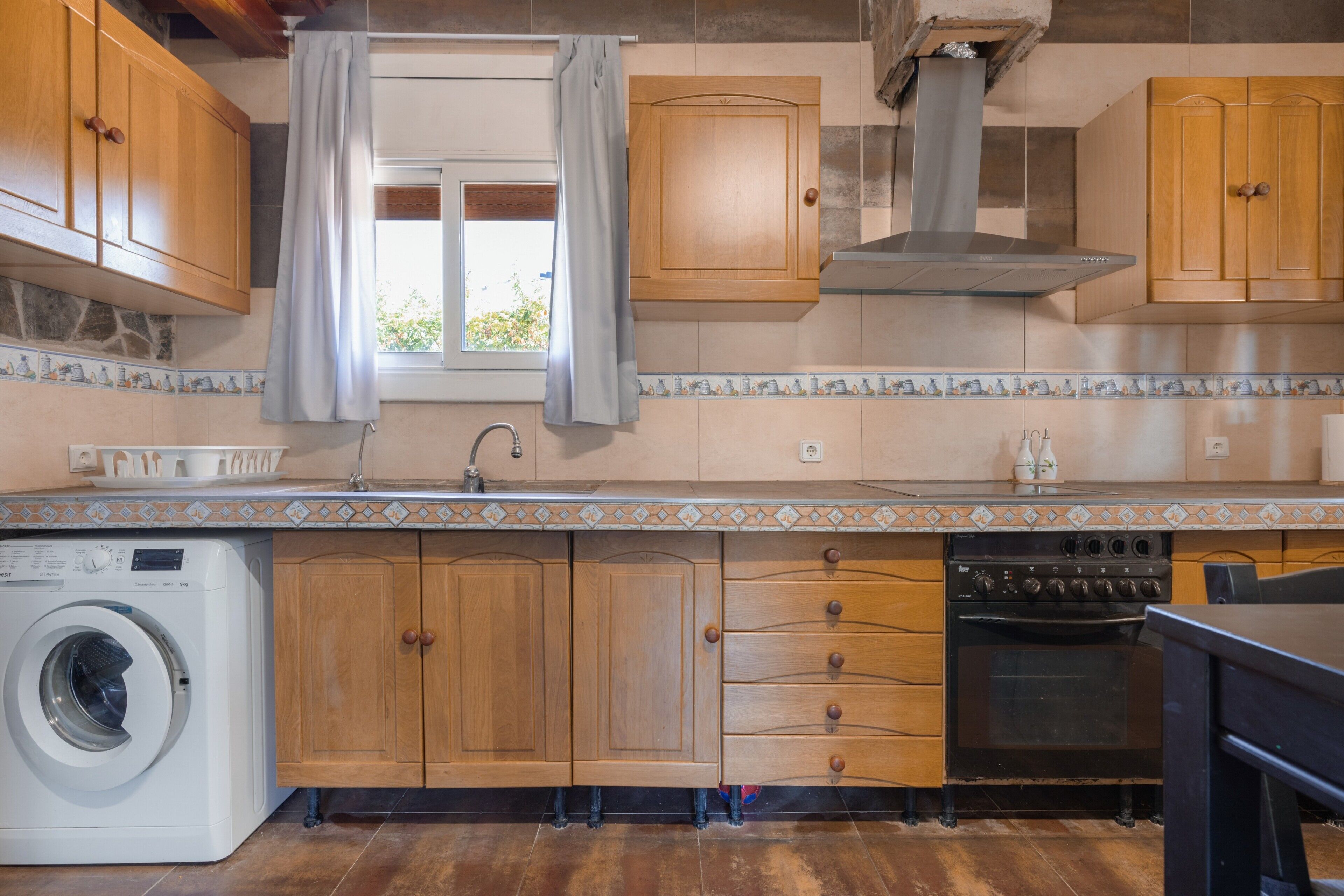 Une cuisine avec des meubles en bois, un lave-linge et une cuisinière.