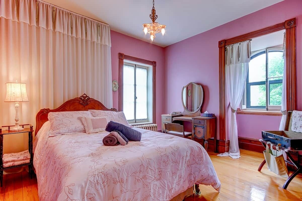 Un dormitorio con cama, escritorio, silla, cómoda, espejo y ventana.