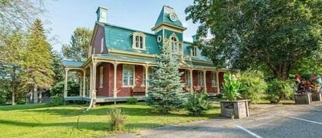 A large, historic building with a prominent turret and a well-maintained lawn.