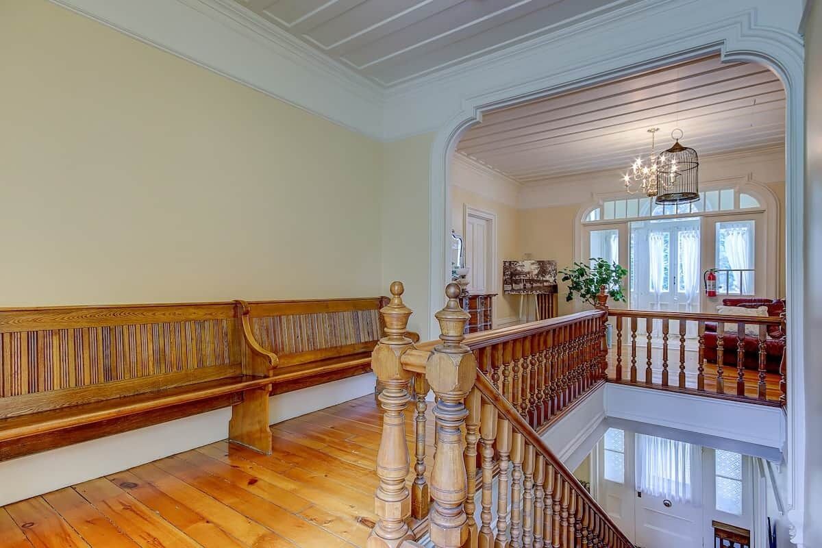 A grand staircase with wooden balustrades, a chandelier, and a view of the upper floor.