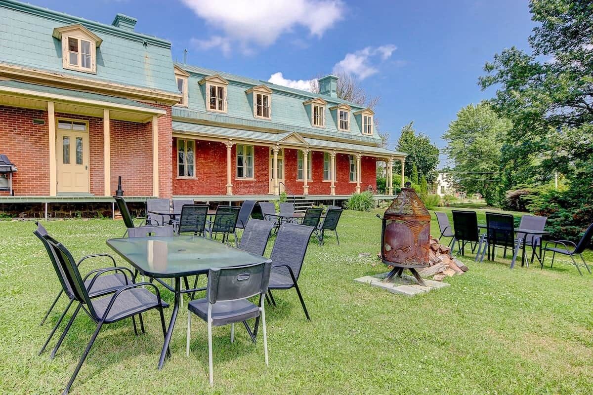 Un edificio con fachada de ladrillo, techo verde y un patio con mesas y sillas.