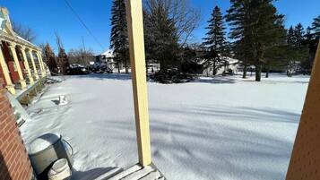 A snow-covered outdoor area with a wooden structure, possibly a porch, and a brick building in the background.