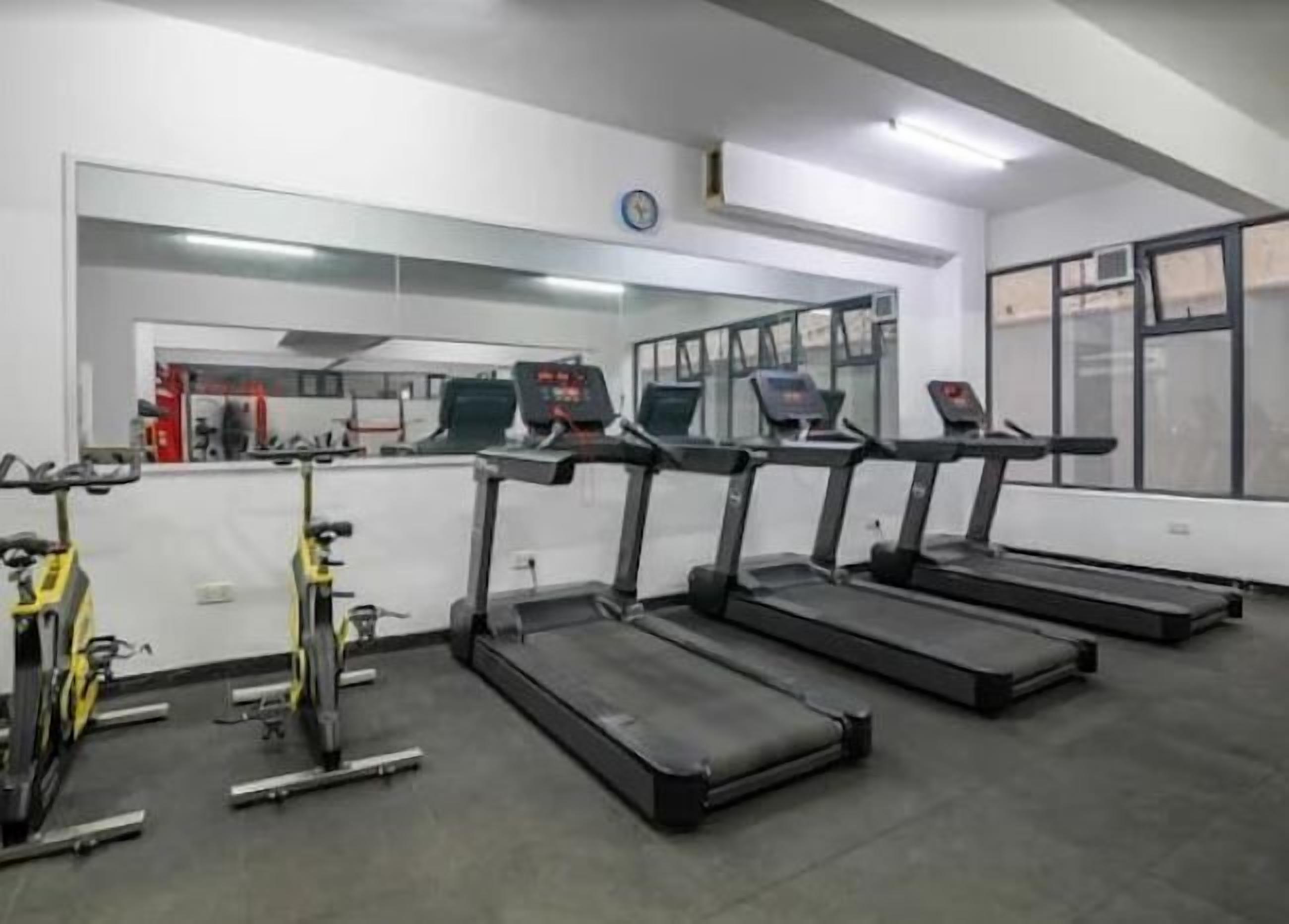 Un gimnasio con cintas de correr, bicicletas estáticas y máquinas de pesas.
