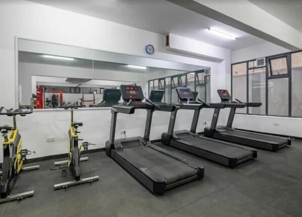 Uma academia com esteiras, bicicletas ergométricas e aparelhos de musculação.