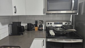 A kitchen with a microwave, stove, coffee maker, and a sink. - Brand new Cozy Basement Suite (Calgary)