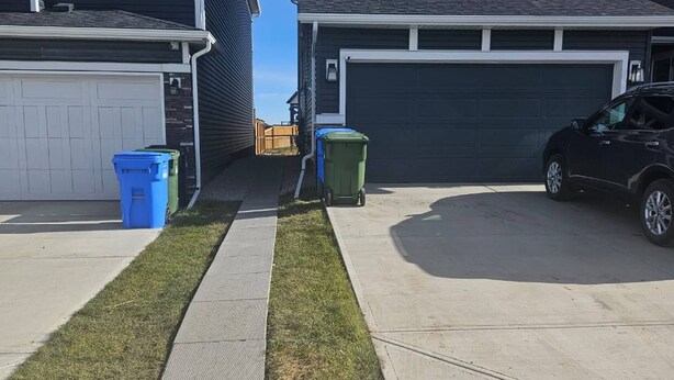 A residential street with two houses, a driveway, and a parked car. - Brand new Cozy Basement Suite (Calgary)