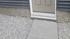 A door with a keypad lock, a small outdoor light fixture above it, and a concrete step leading to the door. - Brand new Cozy Basement Suite (Calgary)