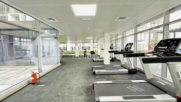 A gym with treadmills, exercise equipment, and large windows.