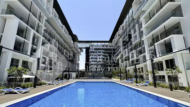 A modern hotel with a central swimming pool, multiple balconies, and a clear sky. - Bloomfields 2br Duplex in Oasis 1  (Abu Dhabi)