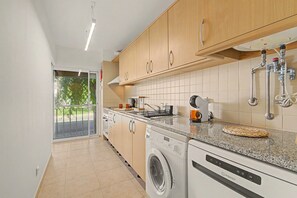 A modern kitchen with a built-in washing machine, a coffee maker, and a sink with visible plumbing.