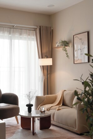 Ein Wohnzimmer mit einer Couch, einem Couchtisch, einer Lampe und einer Pflanze.