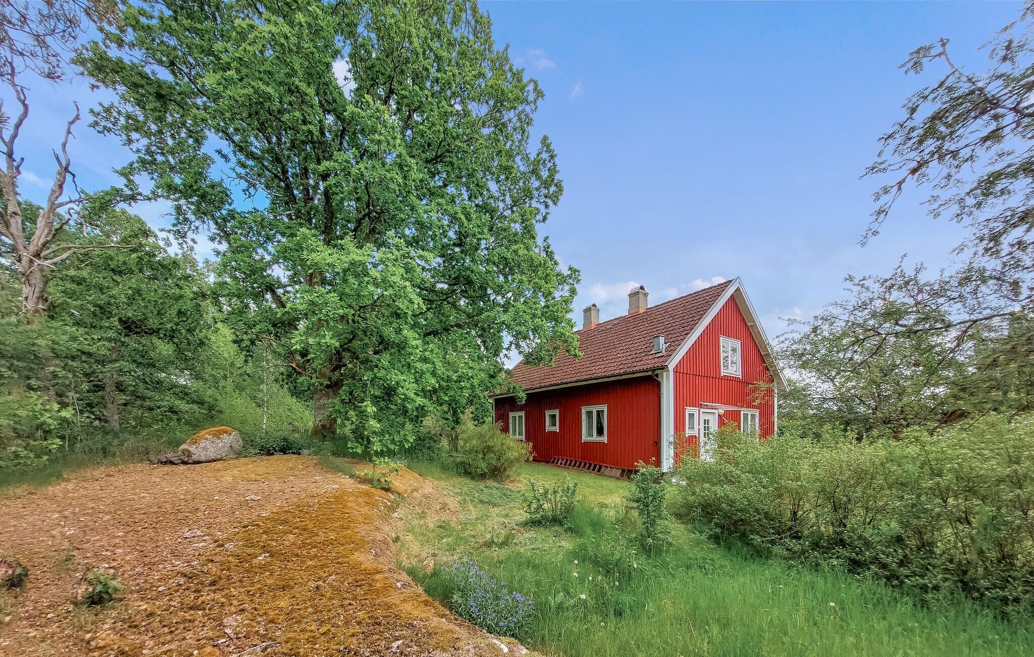 A red house surrounded by greenery and trees.