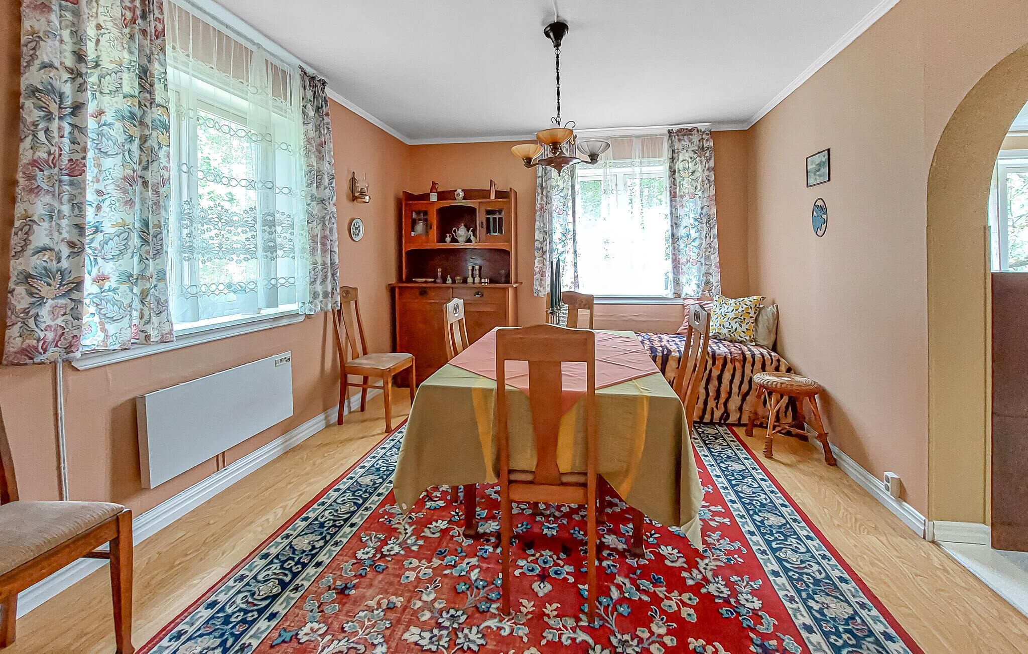 A dining room with a table set for four, a chandelier, and a patterned rug.
