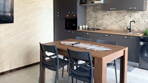 Een moderne keuken met donkere kastjes, een houten eettafel en een ingebouwde wasmachine.