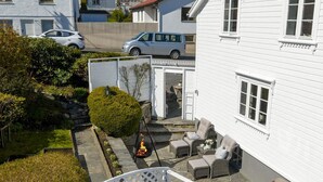 Casa blanca con un sendero de piedra que lleva a un patio con mobiliario exterior y una chimenea.