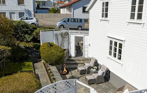 A white house with a stone pathway leading to a patio area with outdoor furniture and a fire pit. - Charming and centrally located detached house by the marina. 3 bedroom, EV charg (Rogaland)