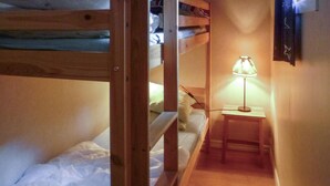 Ein schmaler Flur mit Etagenbetten an einer Seite und einem Nachttisch mit Lampe an der anderen.