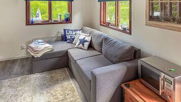 A modern living room with a grey sectional sofa, a small TV, and a wooden cabinet.