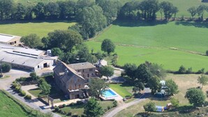 An aerial view of a rural property with a large stone building, a swimming pool, and surrounding fields. - Bed and Breakfast 'Chambre La Paille' with Mountain View, Shared Pool and Wi-Fi (Castelnau-Pégayrols)