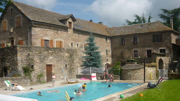 A swimming pool with a stone building in the background. - Bed and Breakfast 'Chambre La Paille' with Mountain View, Shared Pool and Wi-Fi (Castelnau-Pégayrols)