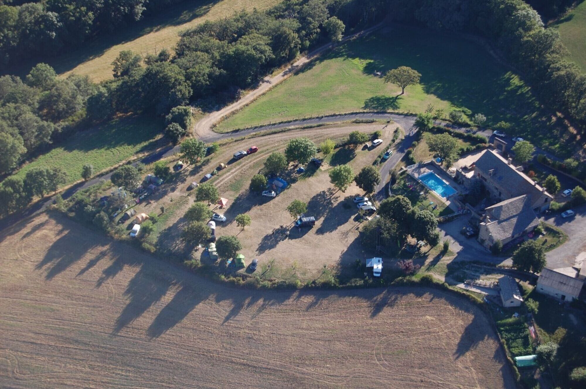 Luchtbeeld van een landelijk gelegen bezit met een zwembad, tenten en een huis.