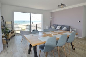 Ein zeitgemäßer Wohnraum mit Essbereich, einer Couch und Meerblick.