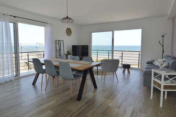 Een ruime woonkamer met balkon, eettafel en een bank.