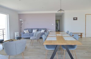 Een moderne woonkamer met een grijze bank, een houten eettafel en grijze stoelen.
