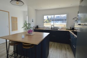 Eine moderne Küche mit einer Holzinsel, dunklen Schränken und einem großen Fenster.
